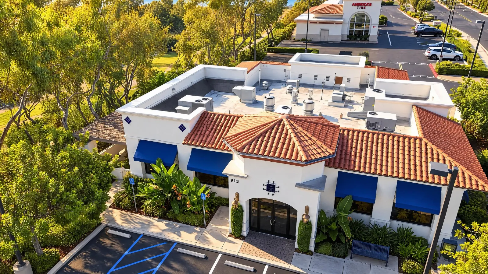 Aerial photograph of 915 Avenida Pico, a white stucco building with a red tile roof and blue awnings